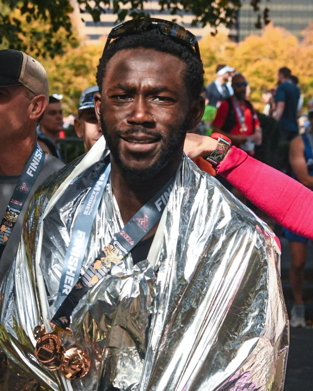 Norm Hamilton at a marathon finish, wrapped in a heat sheet with a finisher medal.